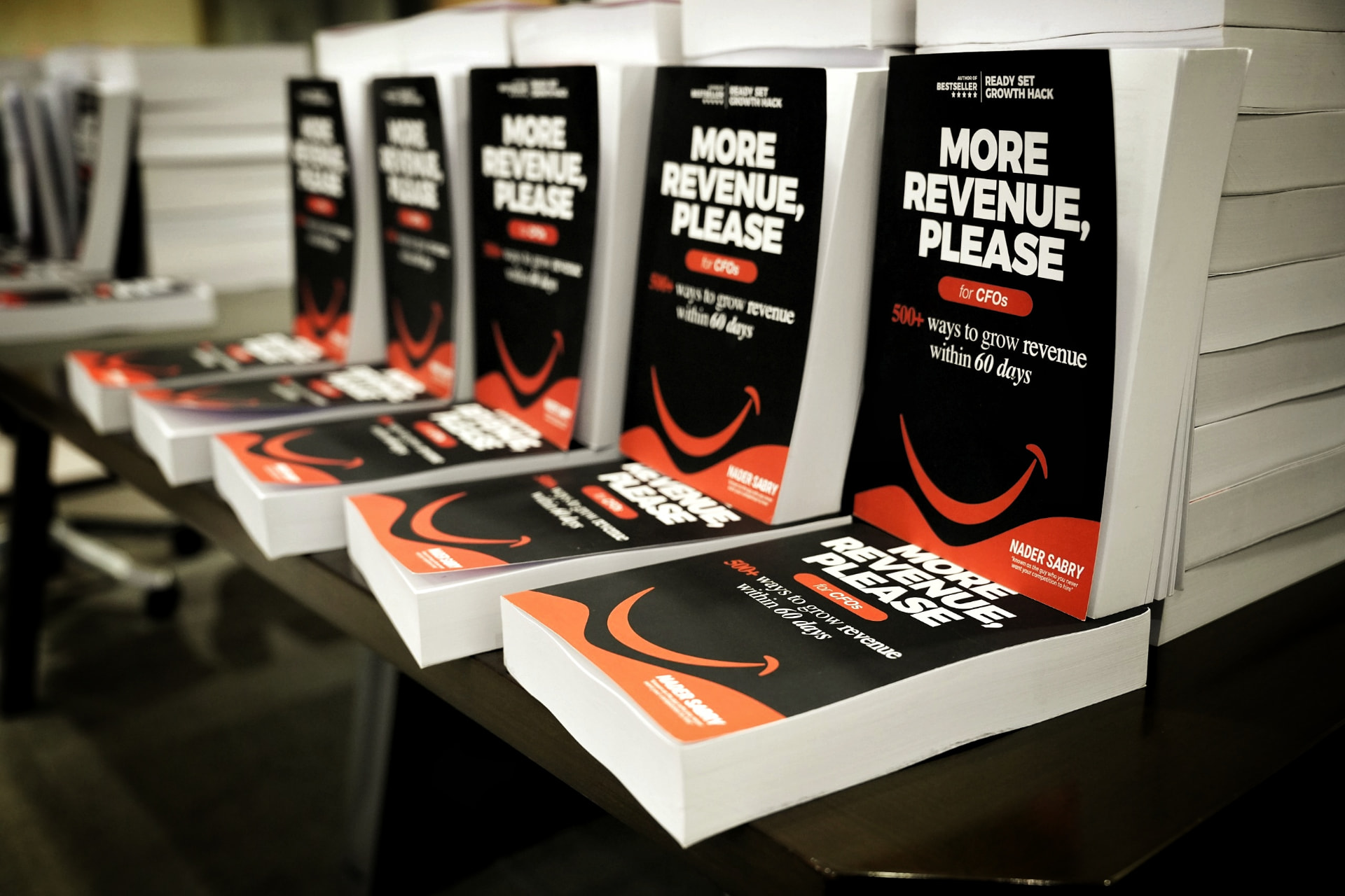 Rows of More Revenue, Please copies stacked on a table